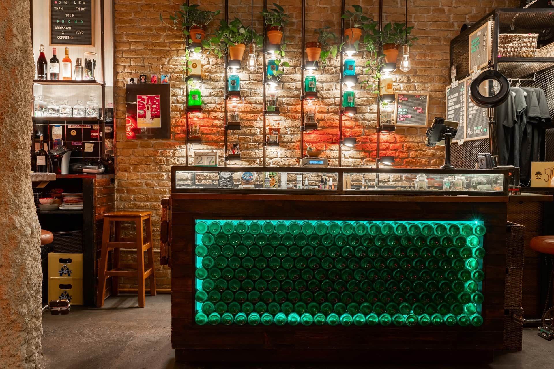 Bancone illuminato di verde e pareti in mattoni nel club sociale della cannabis Dr. Dou Barcellona