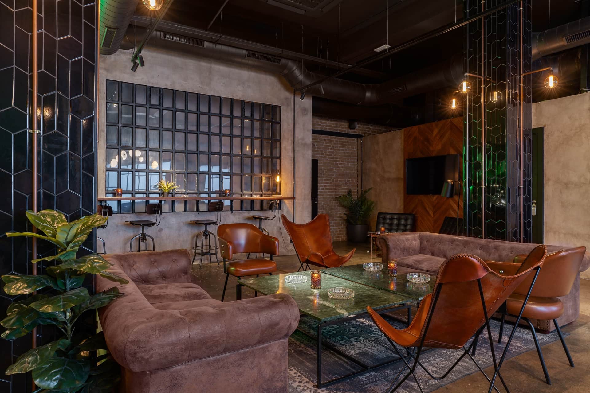 Dr. Resin Barcellona club sociale della cannabis — lounge moderno con divani marroni, tavoli in vetro e piante verdi