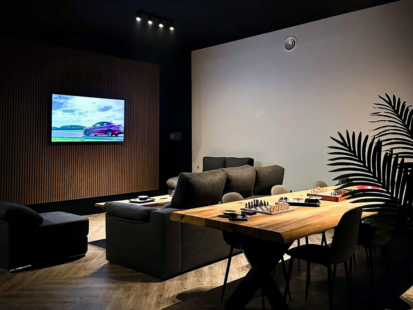 L'accogliente area lounge del cannabis club Four Twenty di Valencia, con divani scuri di fronte a un grande schermo TV su una parete in listelli di legno e scacchiere su un lungo tavolo in legno.