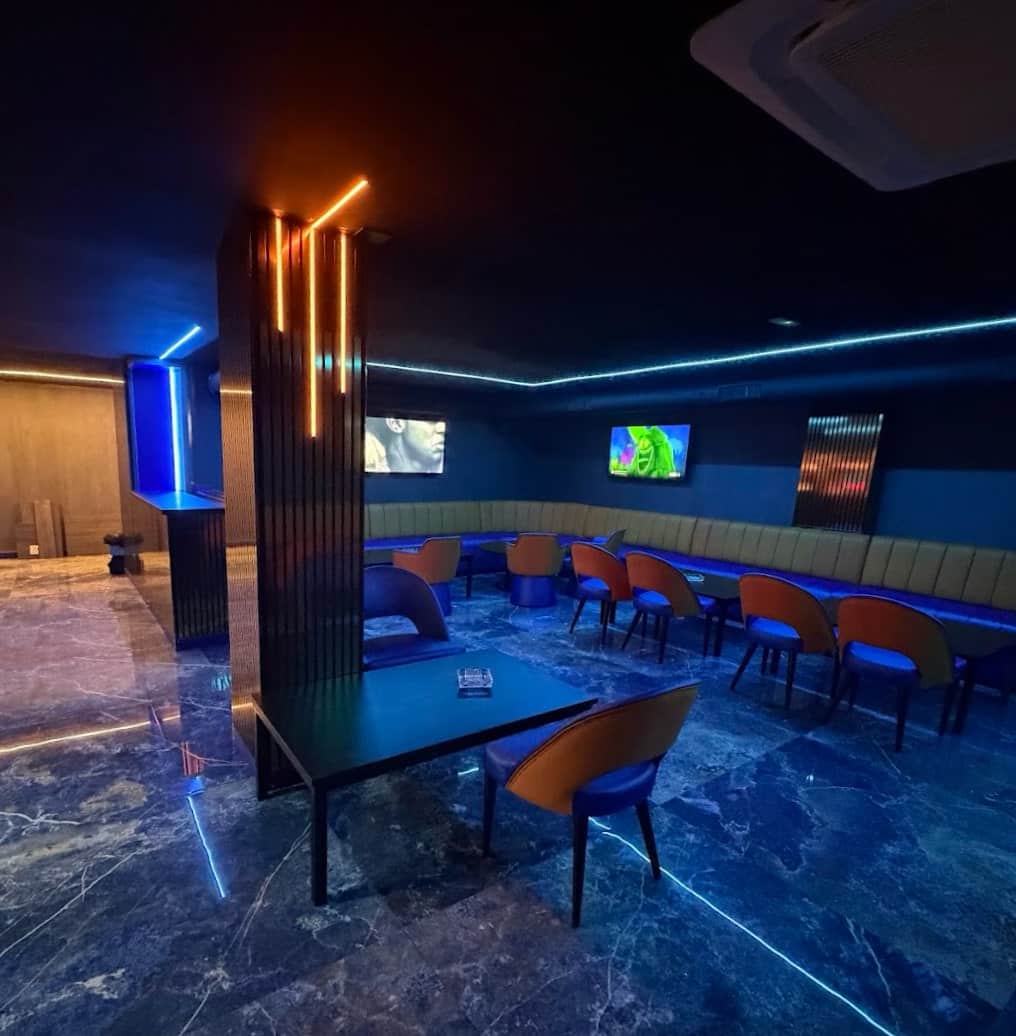 Interno del social club Lux Lounge a Marbella con illuminazione neon blu, panche imbottite e pavimento marmo.