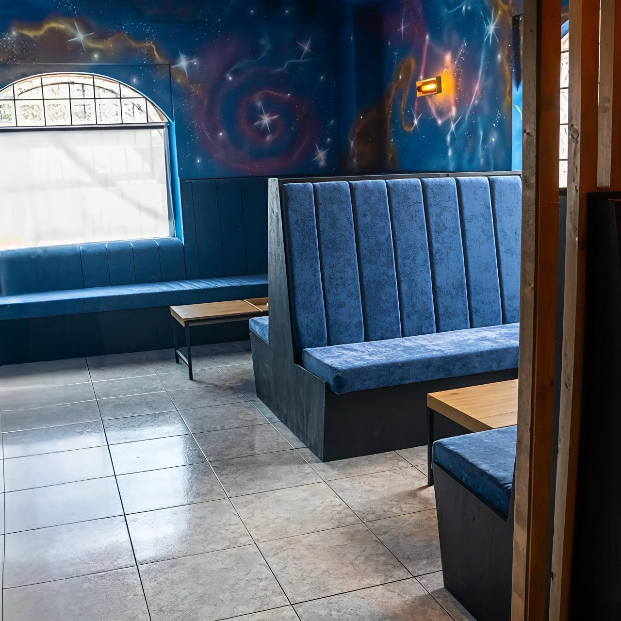 Zona lounge con panche blu e murale spaziale in Sky Alicante