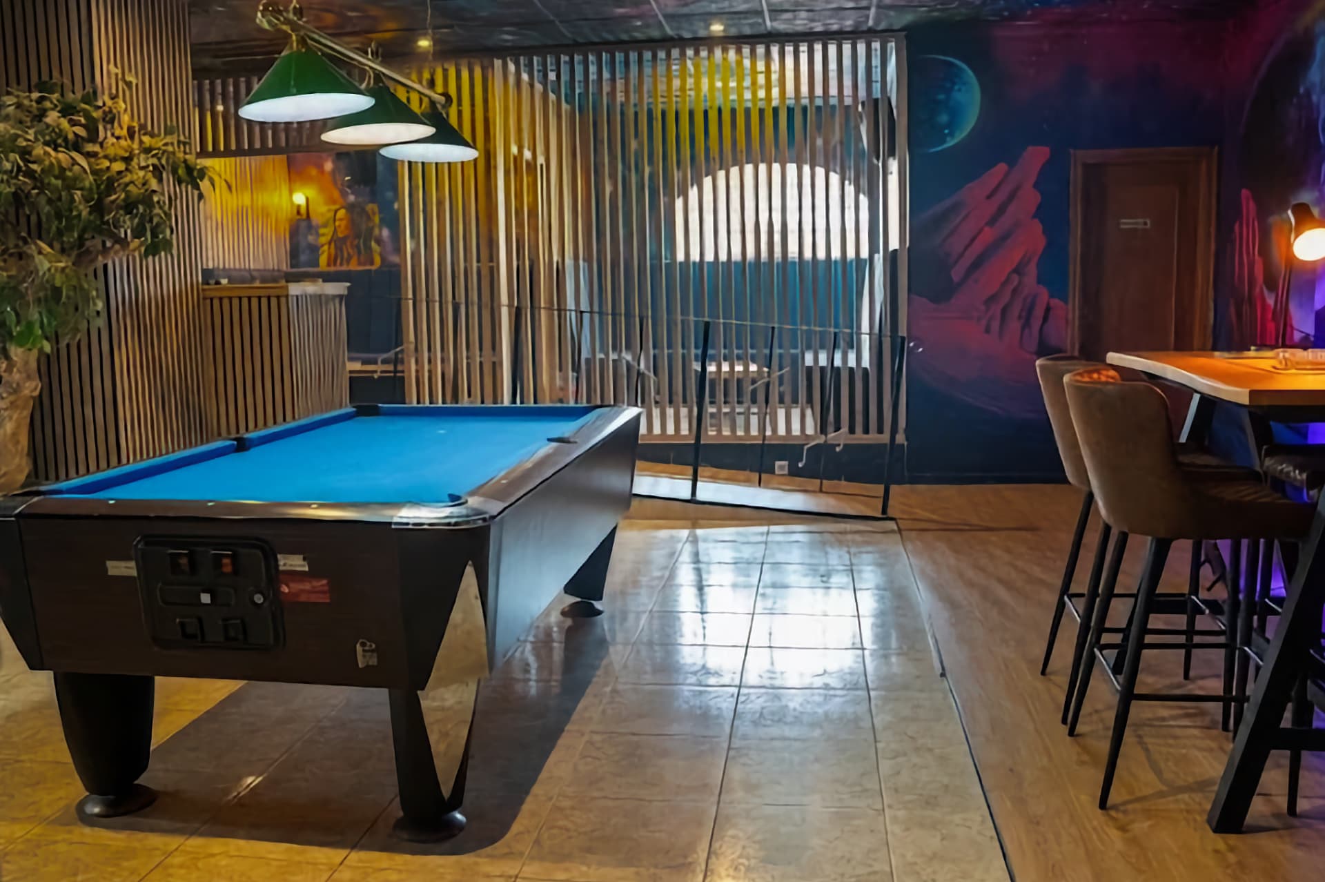 Tavolo da biliardo nel club della cannabis Sky Alicante con murale a tema spaziale e pareti divisorie in legno